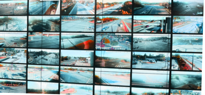 A grid of multiple security and traffic camera feeds displayed on a wall, showcasing live intersections, roads, and infrastructure for smart city monitoring.